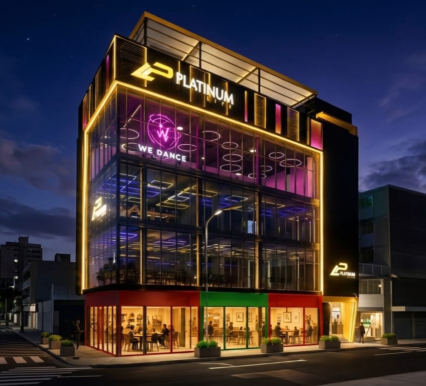 Local Platinum Life iluminado de noche — fachada de vidrio con letrero WE DANCE